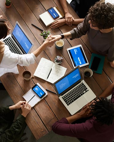 pexels-photo-3183148-3183148 A diverse group of professionals brainstorming in a modern workspace with laptops and notebooks.