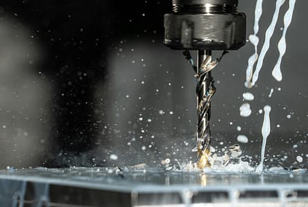 pexels-photo-8956313-8956313 High-speed close-up of CNC drill bit in action with water splash for lubrication.