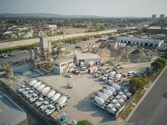 pexels-photo-9716233-9716233 Aerial shot of a bustling cement manufacturing plant with mixer trucks and industrial equipment.